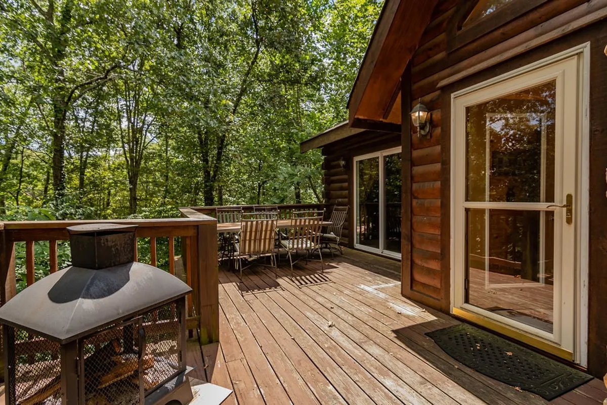 This image features a spacious wooden deck with a comfortable outdoor seating area and a fire pit, surrounded by lush greenery. The scene evokes a peaceful, relaxing atmosphere perfect for unwinding or entertaining guests under the stars.